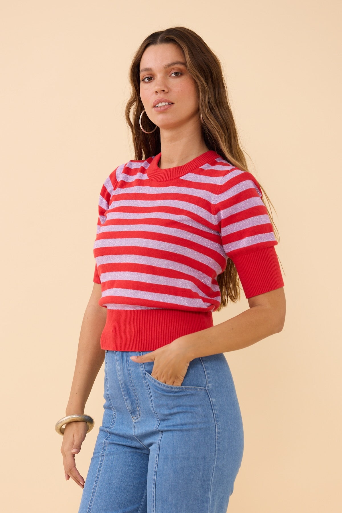 Woman wearing the Frock Me Out RED and DISCO LILAC Stripe Knit paired with Blue high waisted pants